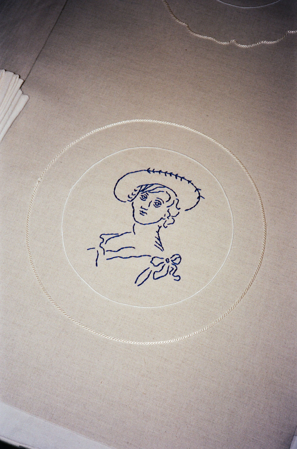 Blue embroidered portrait of a woman in a hat on a linen placemat