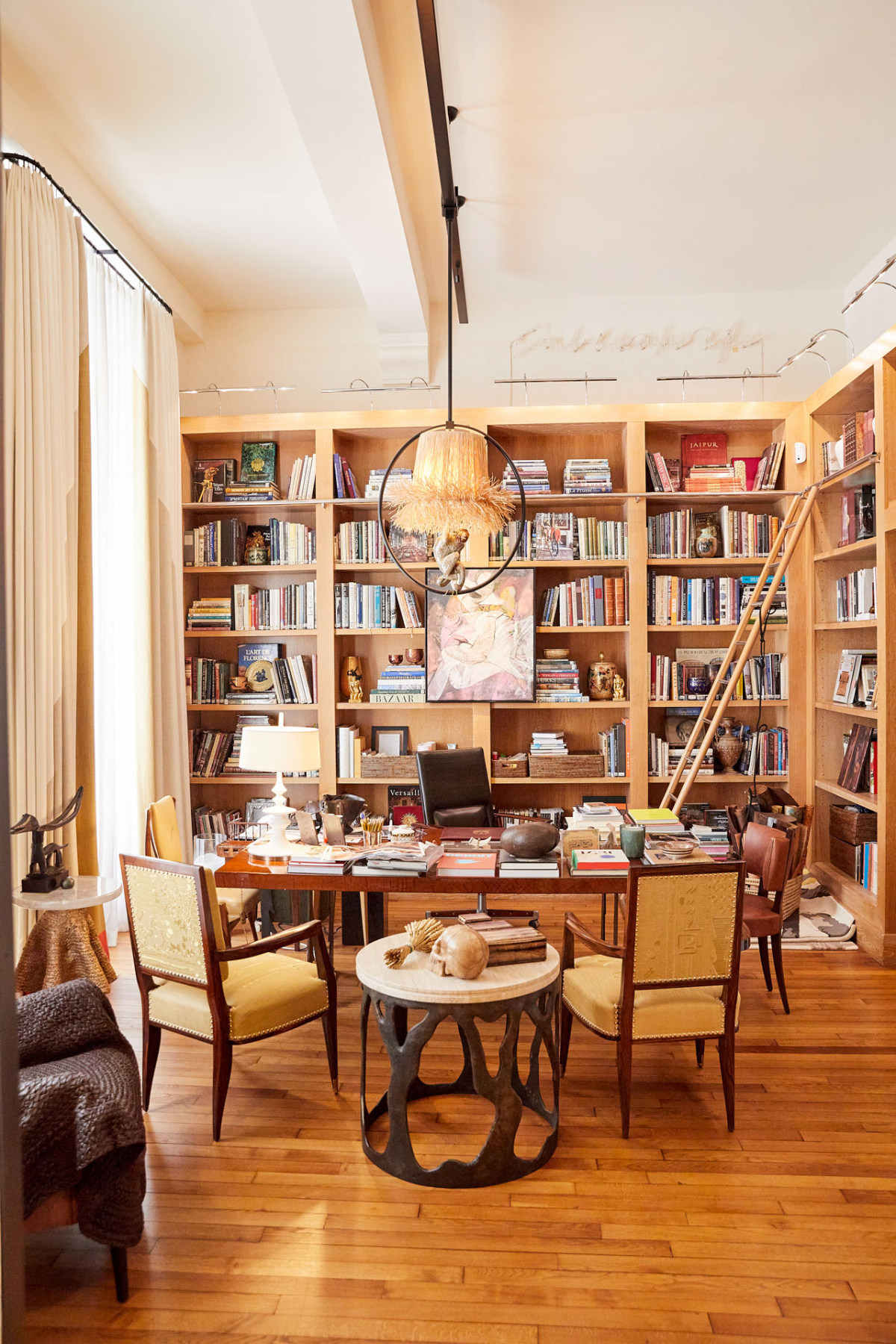 Library with floor-to-ceiling bookshelves, a rolling ladder, and a desk