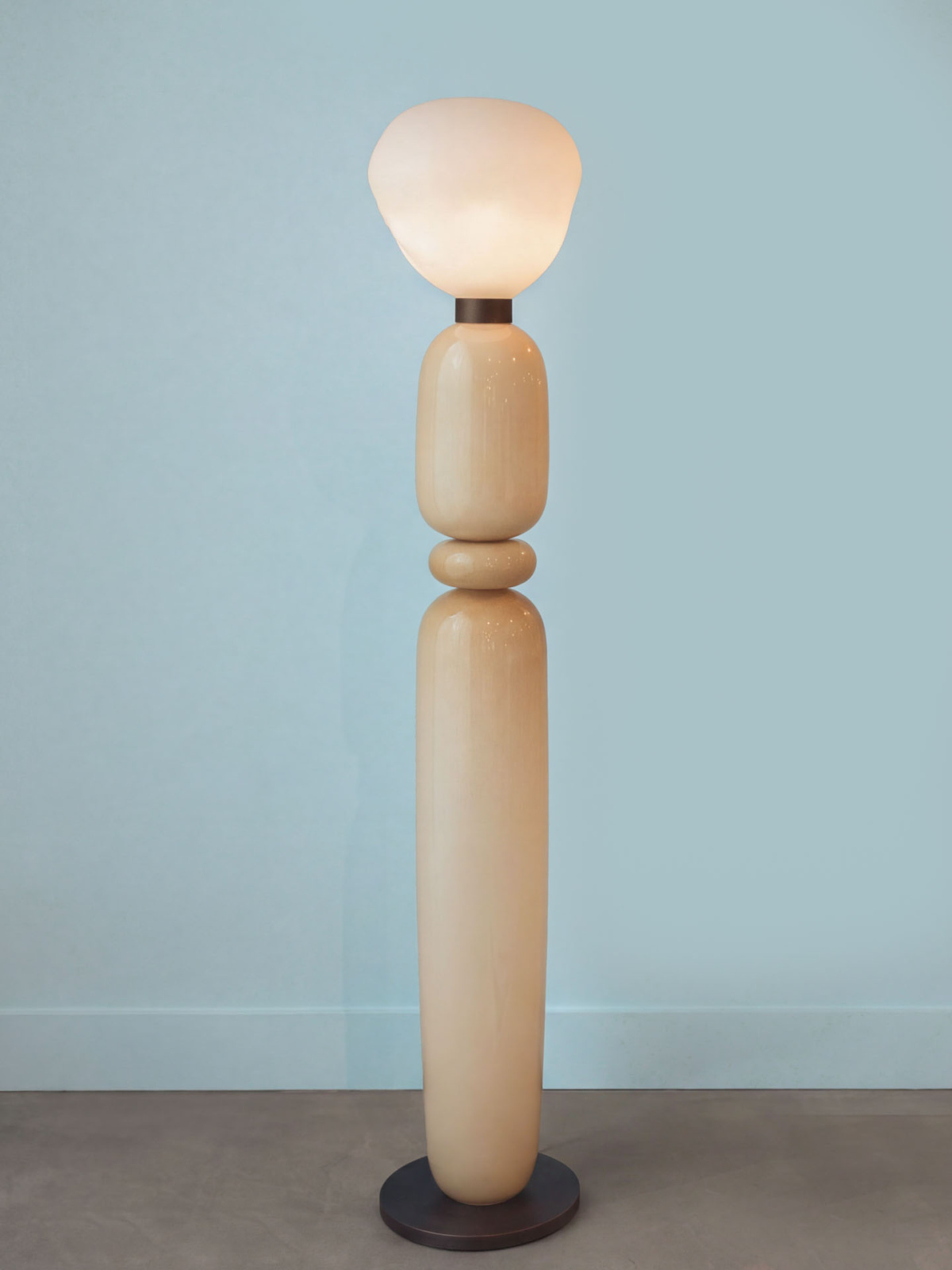 Pale stacked glass floor lamp against a light blue wall