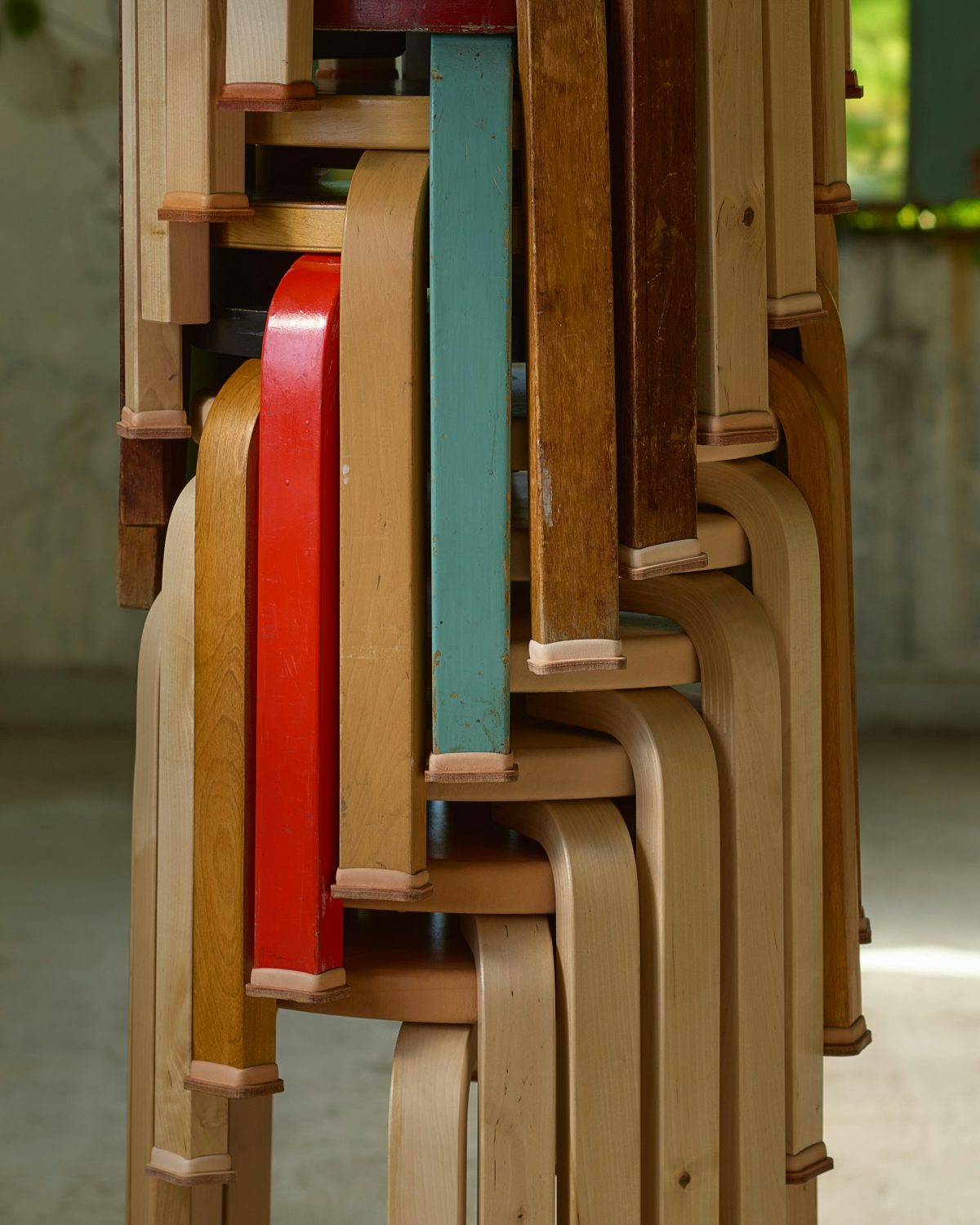 Stacked Artek Stool 60s in painted and natural finishes with natural leather caps on the birch legs.