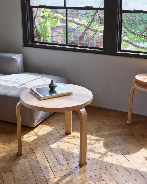 Artek Table 90C with a natural leather top beside a window, with two leather-topped Stool 60s stacked behind it.