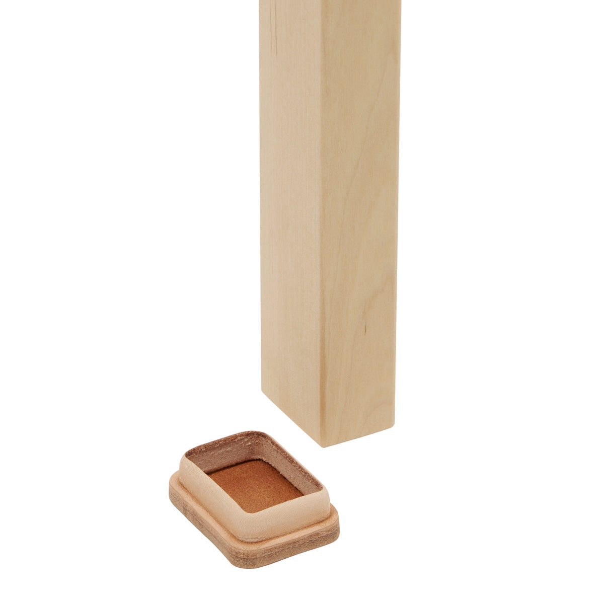 A natural leather Stool 60 shoe on a white background beside the end of a birch stool leg.