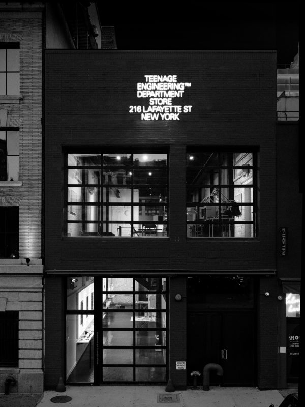 Teenage Engineering's store at 216 Lafayette Street in New York at night, with its name in neon over a black brick facade.